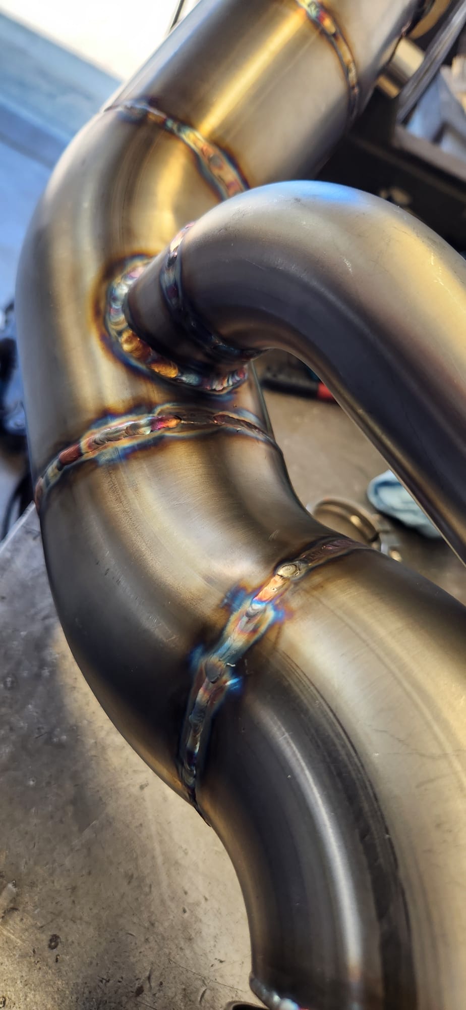 Custom stainless exhaust header collector welds with rainbow heat tint from back-purge TIG welding