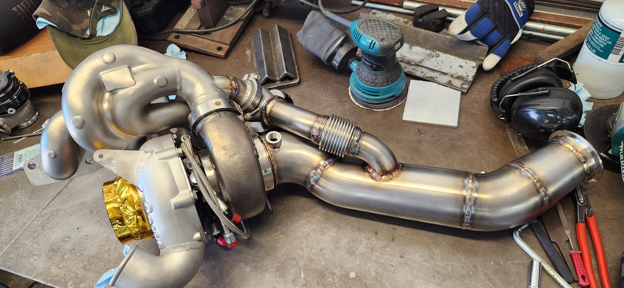 Garrett turbo with custom stainless downpipe and flex section on workbench