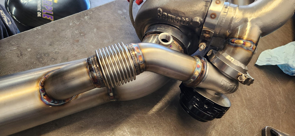 Close-up of back-purged TIG weld on stainless bung and V-band flange — angle 3