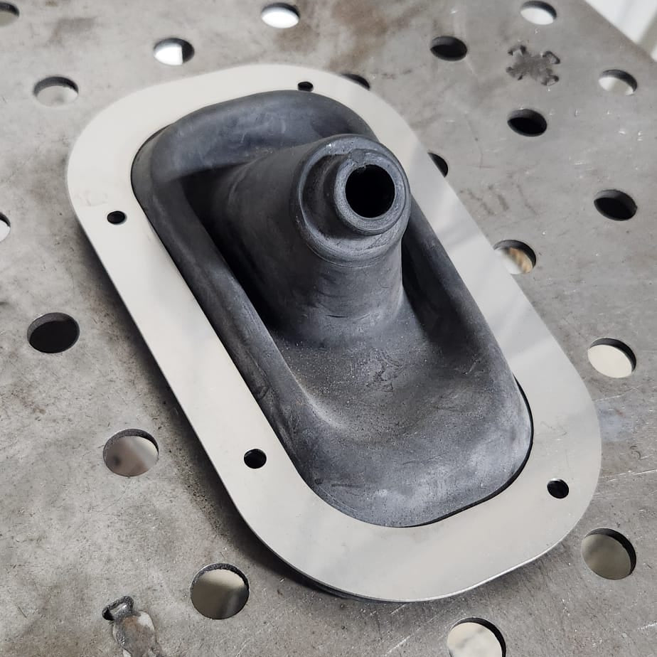 S30Z stainless shift boot ring with OEM rubber boot installed on welding table