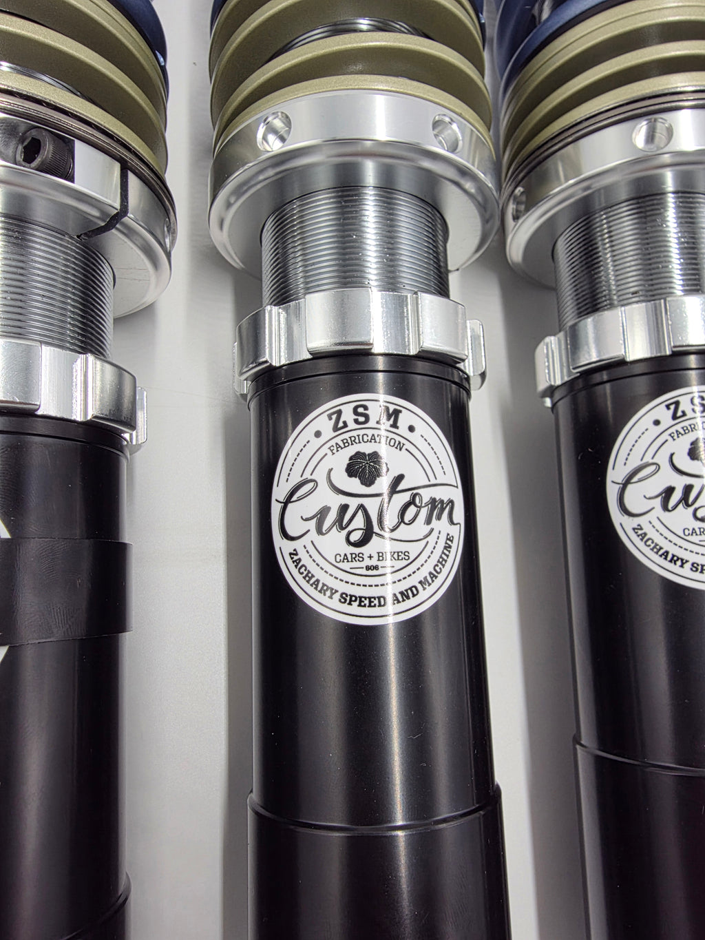 Three ZSM S30Z coilovers standing upright showing ZSM Custom badge